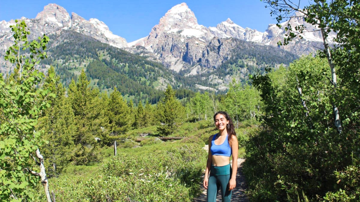 Editora de Travel Lemming, Abigail posando con el Parque Nacional Grand Teton de fondo en un día soleado