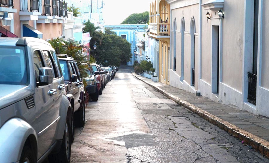 Vista de autos estacionados en un callejón con casas coloridas