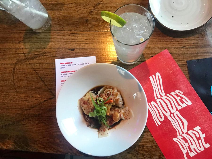Un plato de albóndigas con fideos y un vaso de bebida con limón en Glo Noodle House