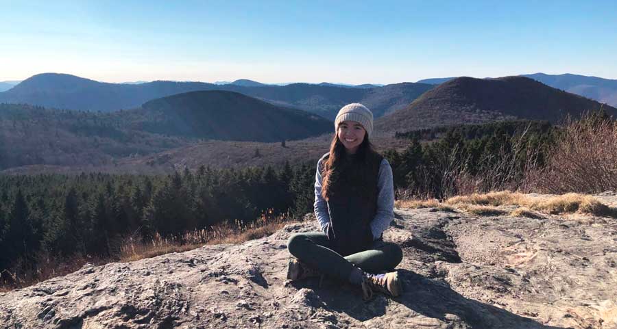 La autora sentada en la cima de una montaña durante una de sus caminatas en Asheville.