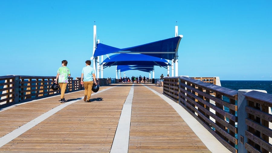 Vista de personas caminando en el paseo marítimo del muelle público de Pompano Beach