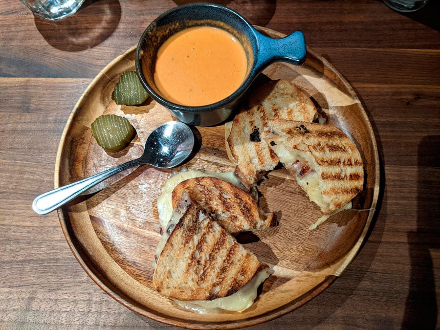 El queso a la parrilla OMG con salsa en un plato de madera en Postino