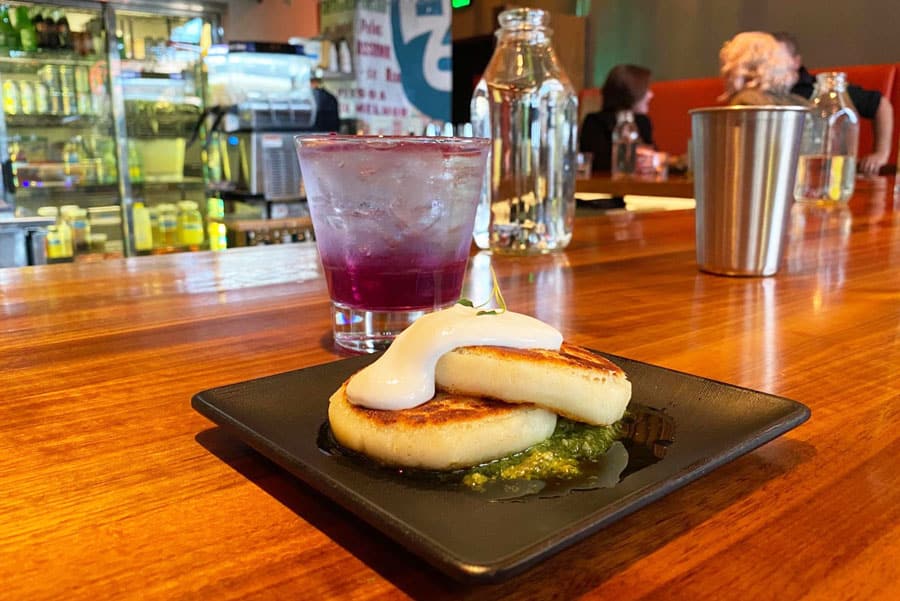 Arepas de Queso en un plato y un vaso de bebida en SuperMegaBien