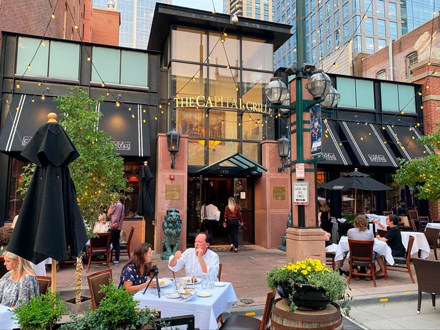 Personas disfrutando de su comida en el comedor al aire libre en The Capital Grille