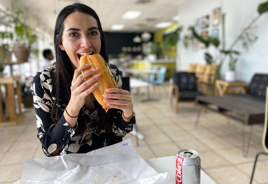 Clara comiendo un primer bocado de tofu banh mi en Vinh Xuong Bakery